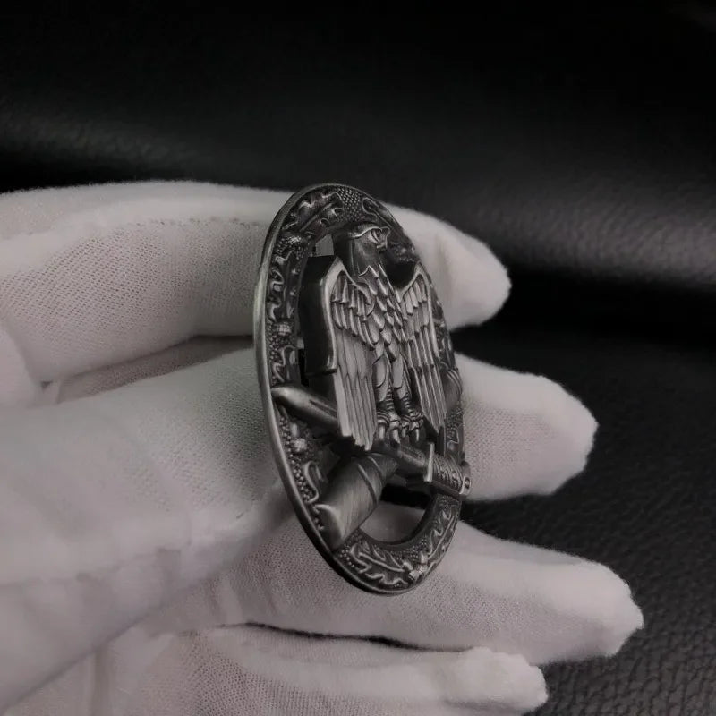 Close-up of a German assault operations medal with detailed eagle design, held in a gloved hand