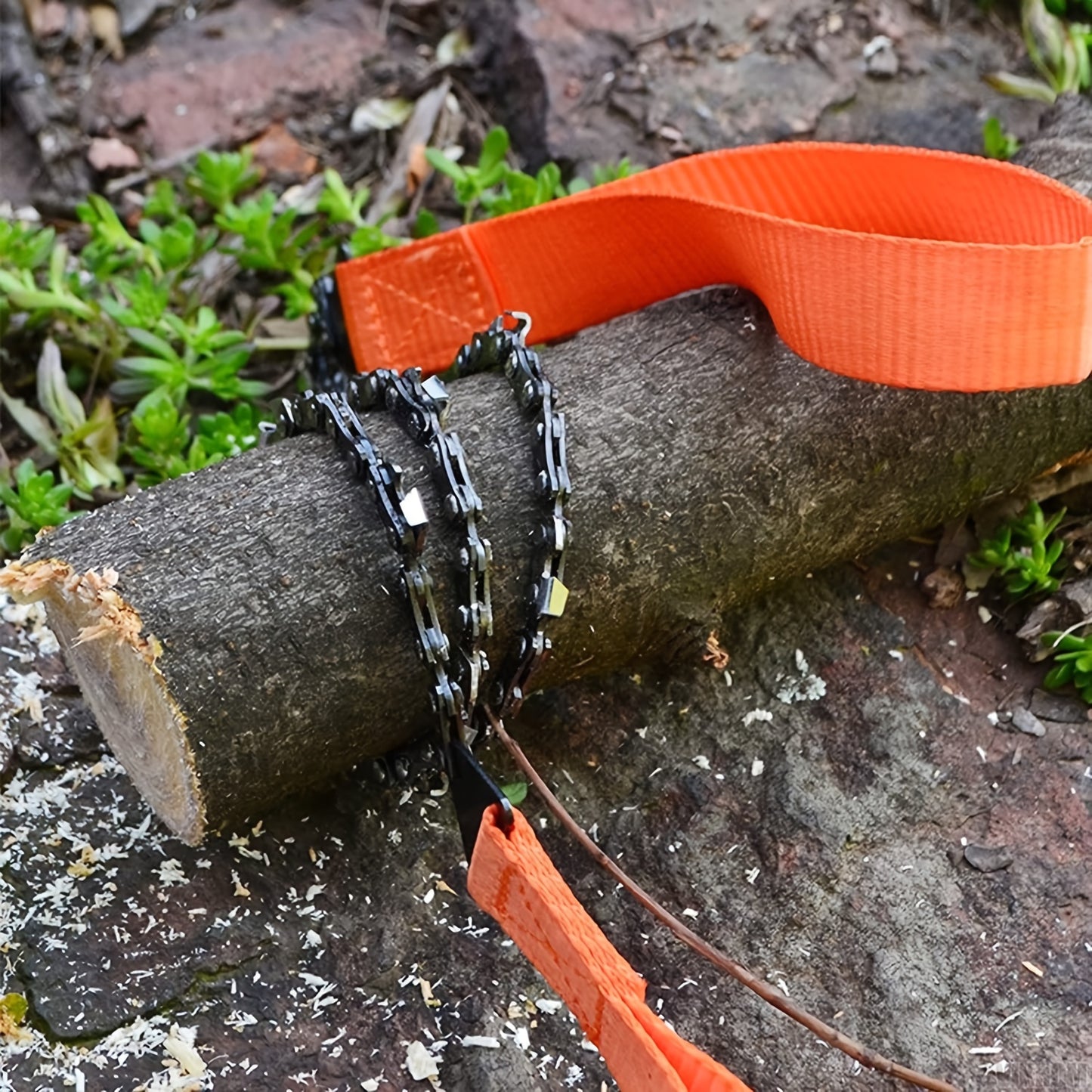 Ultimate pocket chainsaw with durable orange straps cutting through a tree branch outdoors