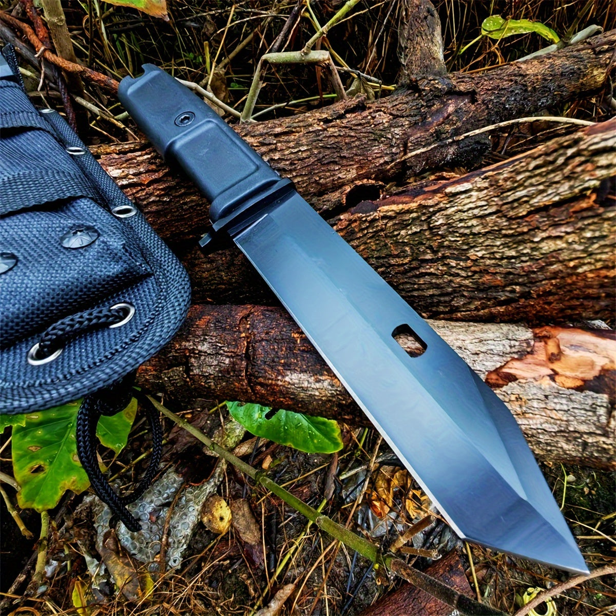 Black tactical wilderness survival multi-purpose knife with full tang blade and nylon sheath on forest floor