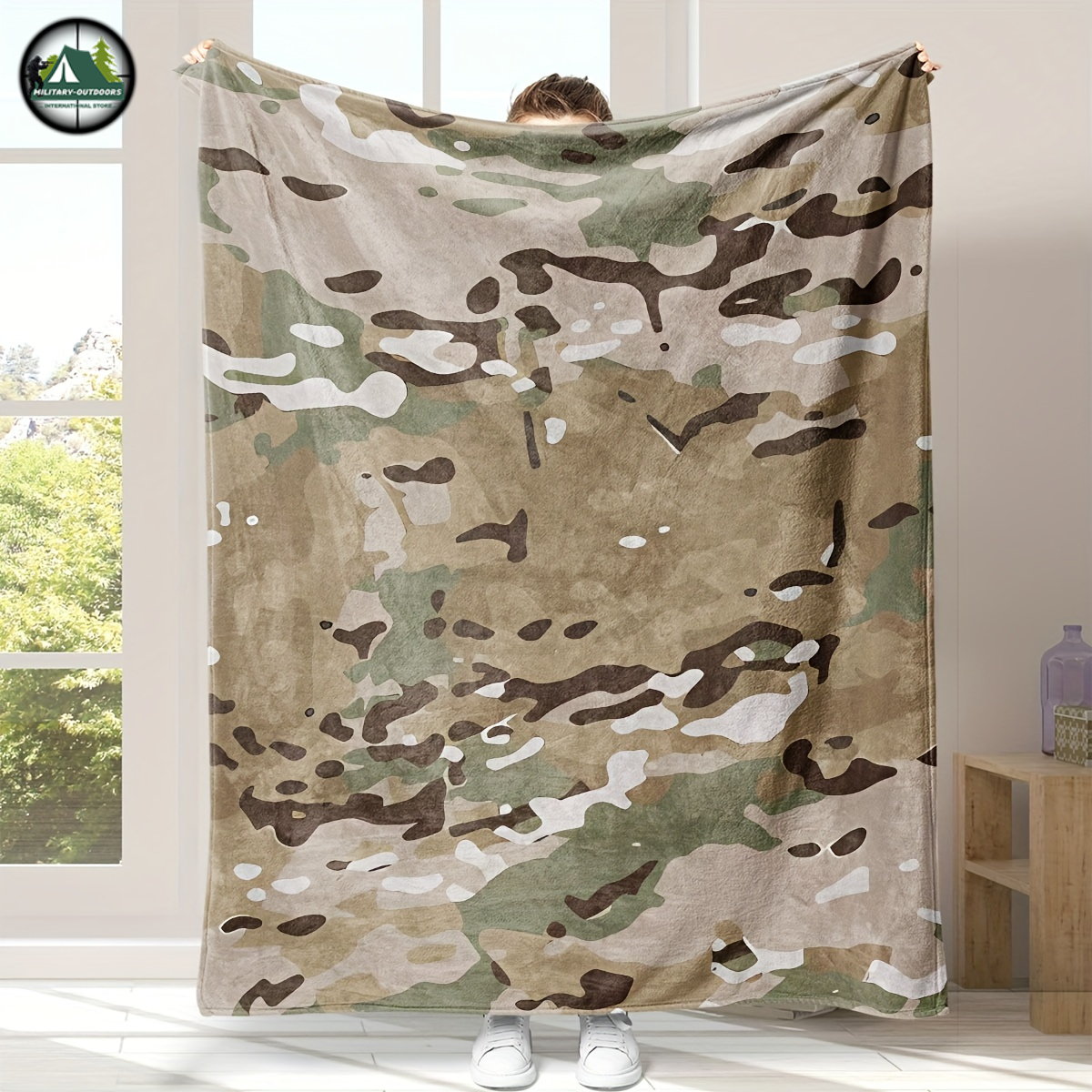 Camouflage flannel blanket with military-inspired pattern held up indoors by a person from Military-Outdoors.com