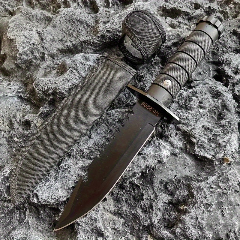 Military-Outdoors.com hunting and camping knife with black serrated blade and textured handle on rocky surface