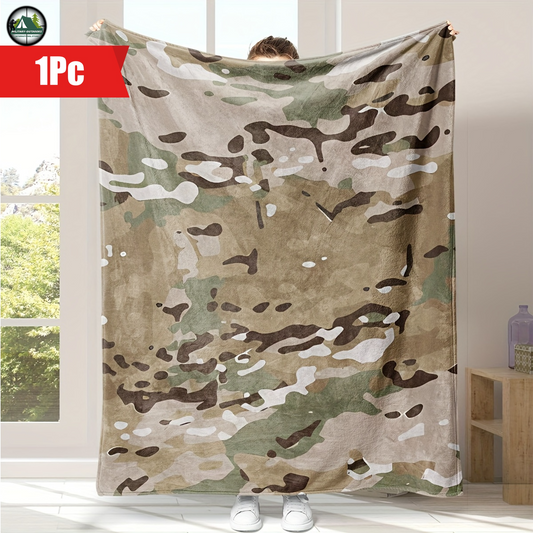Camouflage flannel blanket with green brown and tan colors held up indoors by person