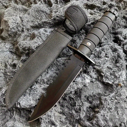 Military-Outdoors.com hunting and camping knife with black serrated blade and textured handle on rocky surface